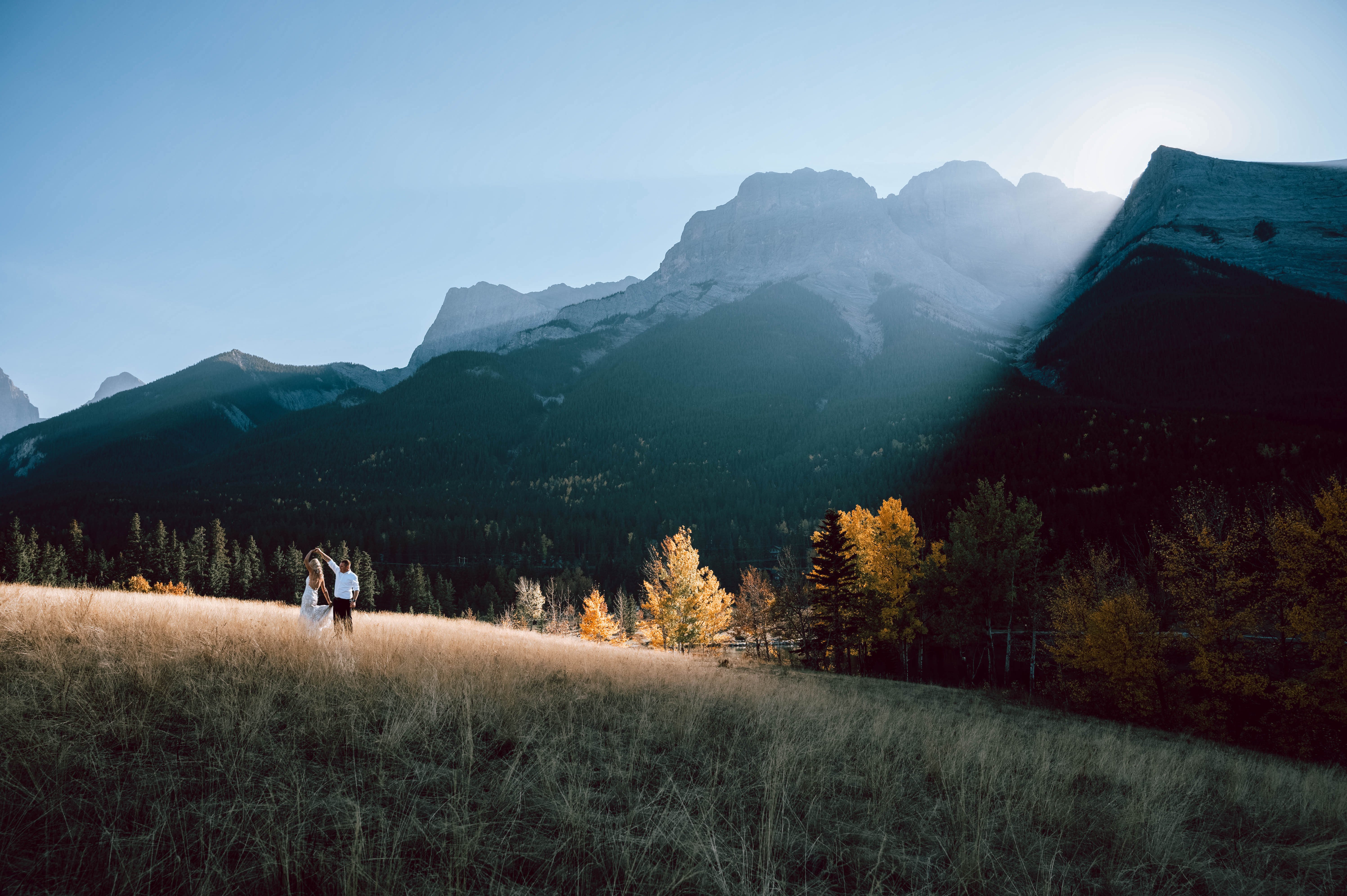 Couple dancing in the sunlight over the rocky mountains