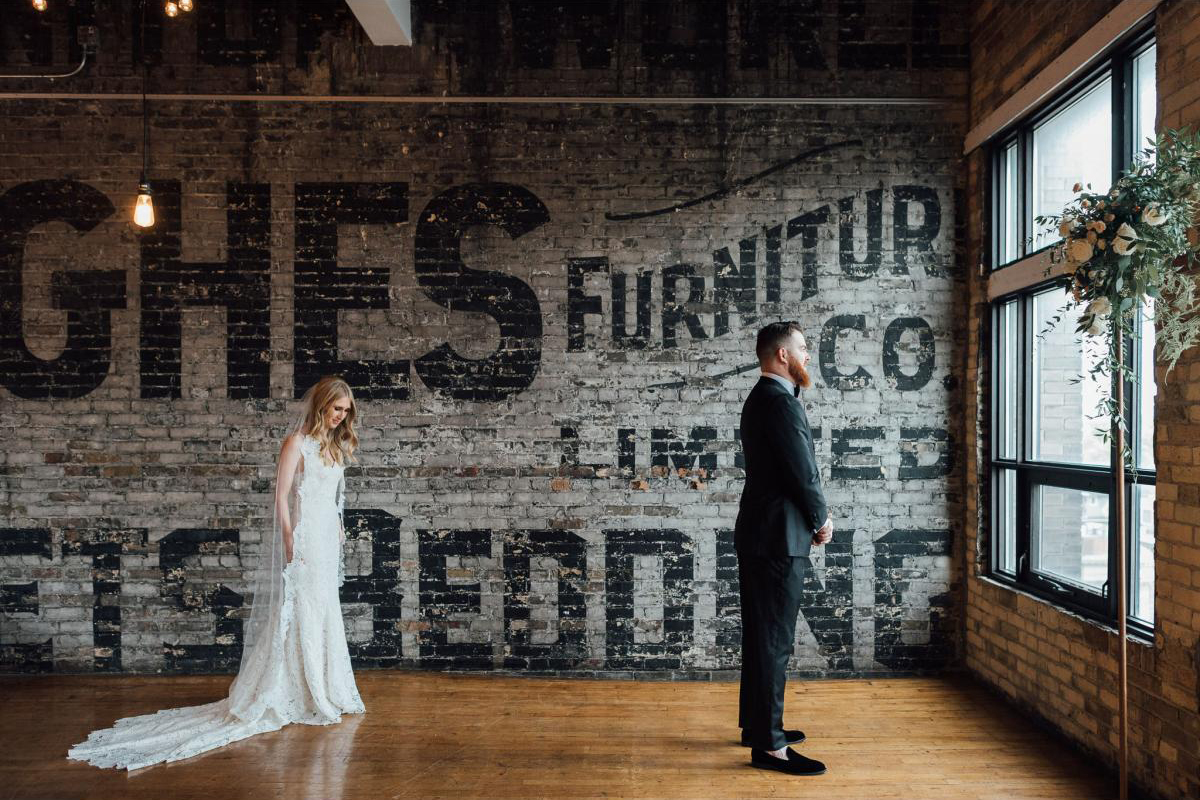 Bride walks up to groom for first look inside industrial building