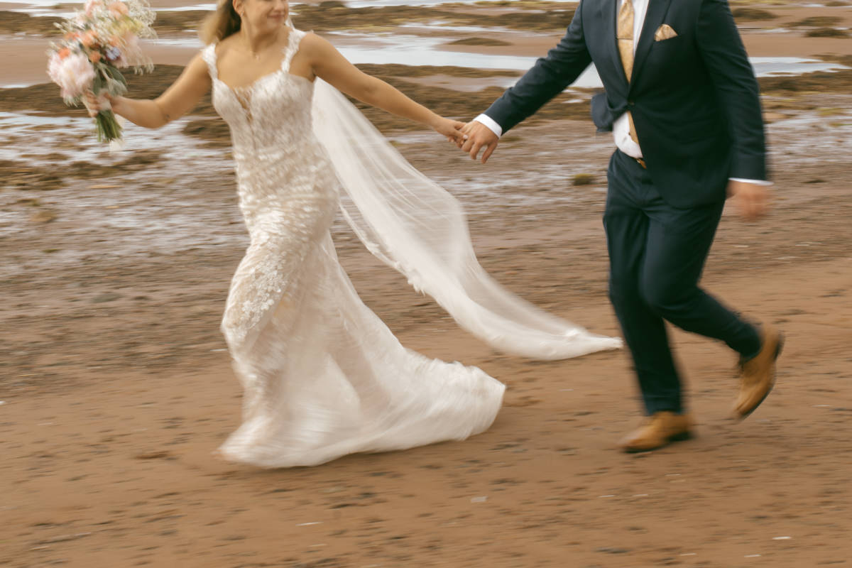 Bride and groom running along the beach at Thinkers Lodge, Pugwash, NS