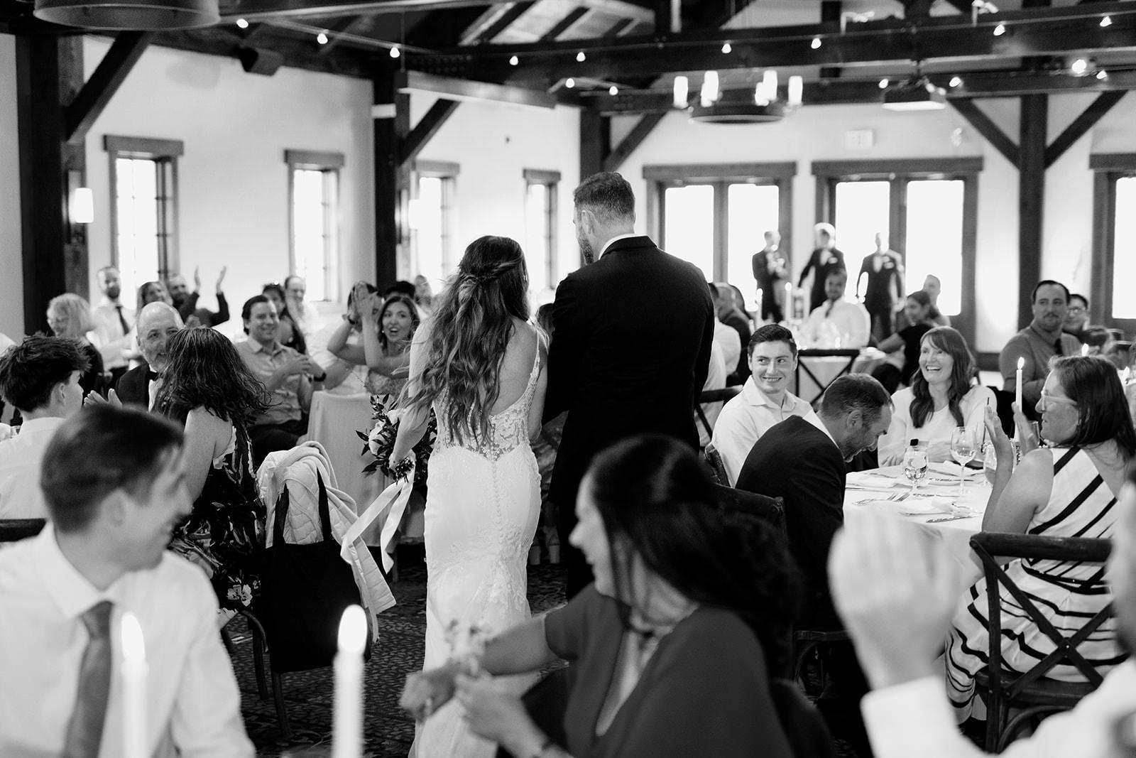 Black and white photo of couple making their grand entrance to their reception at Silvertip Pavilion