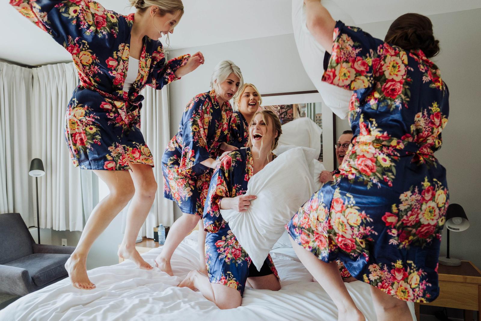 Bridesmaids having pillow fight in bridal robes