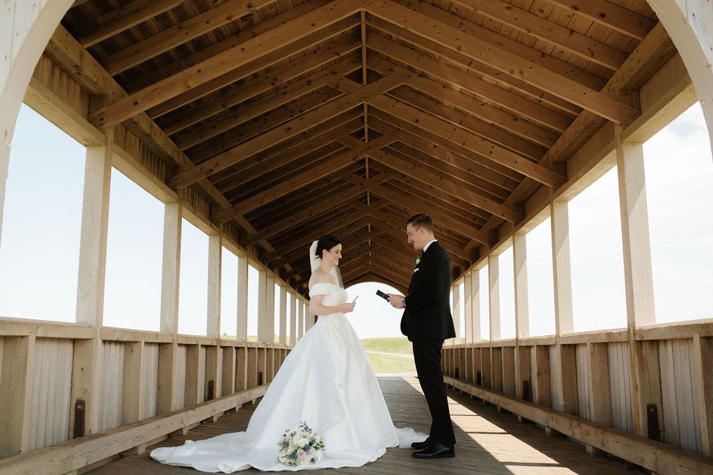 Bride and groom exchange vows under a covered bridge at Fox Harb'r resort, Nova Scotia
