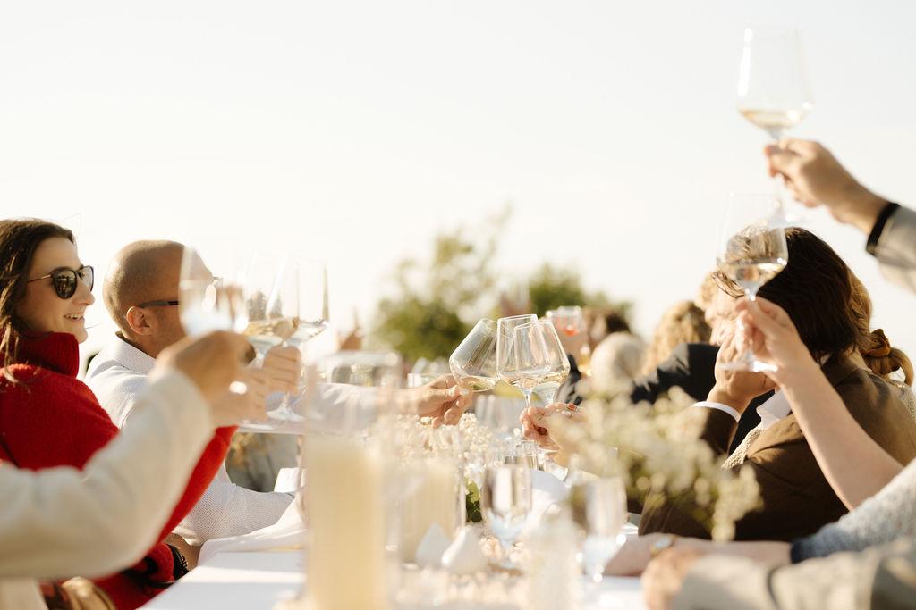 Wedding guests cheers with wine glasses across the dinner table, Fox Harb'r, Nova Scotia