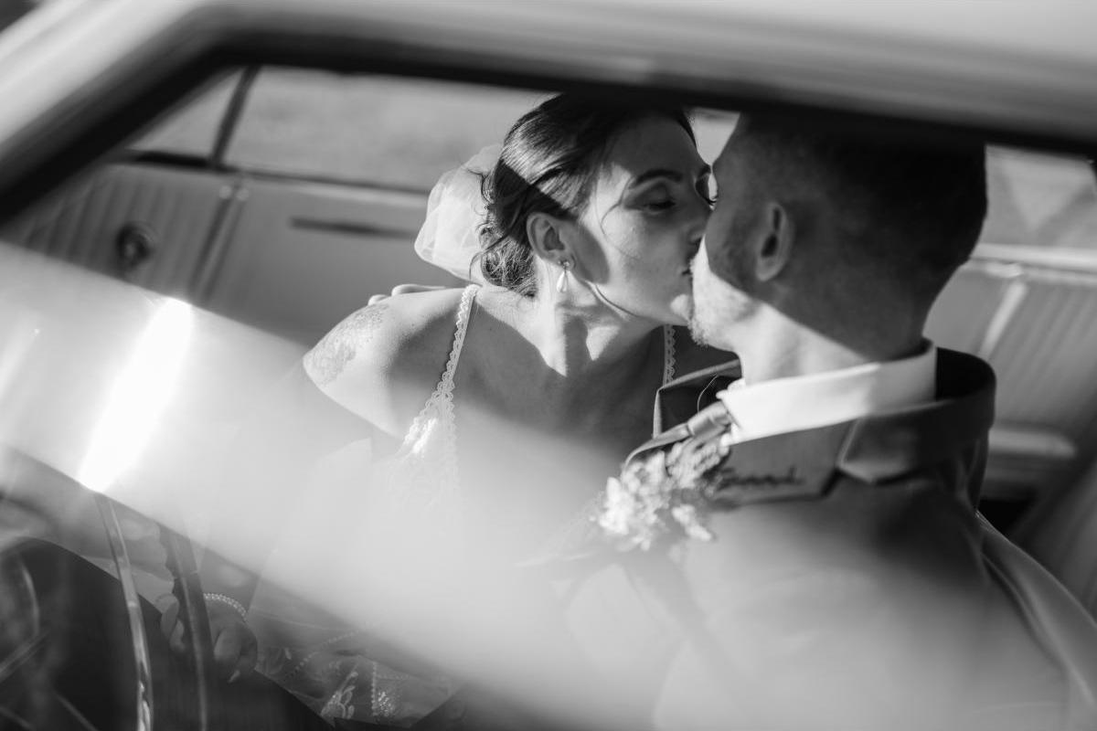 Bride and groom kissing in car