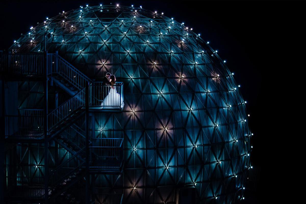 Creative night portrait of bride and groom in front of glowing structure, windsor, ontario