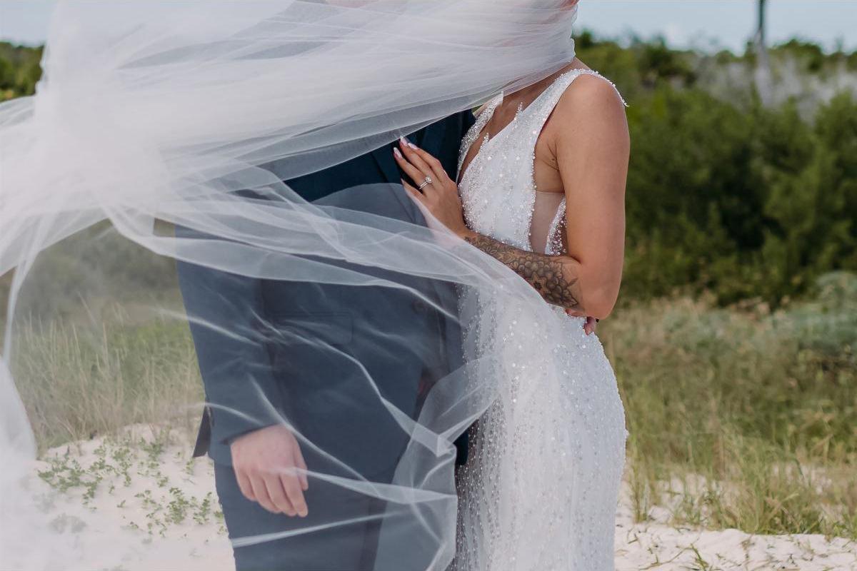 Bride and groom covered in windswept veil in Kelowna