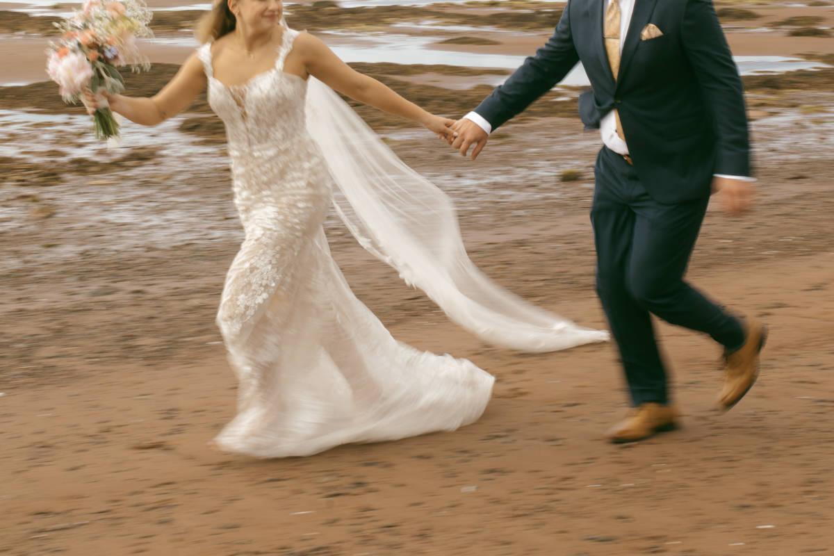 Bride and groom running along the beach at Thinkers Lodge, Pugwash, NS