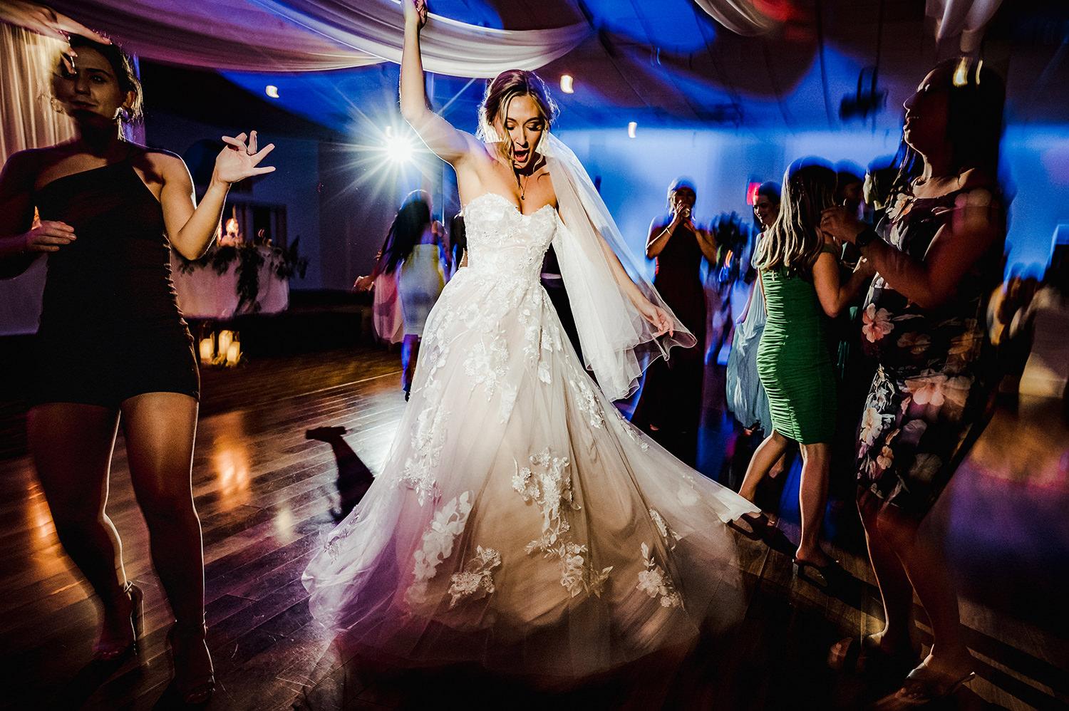 Energetic bride on the dance floor by Winnipeg photographers Black & Gold Photography